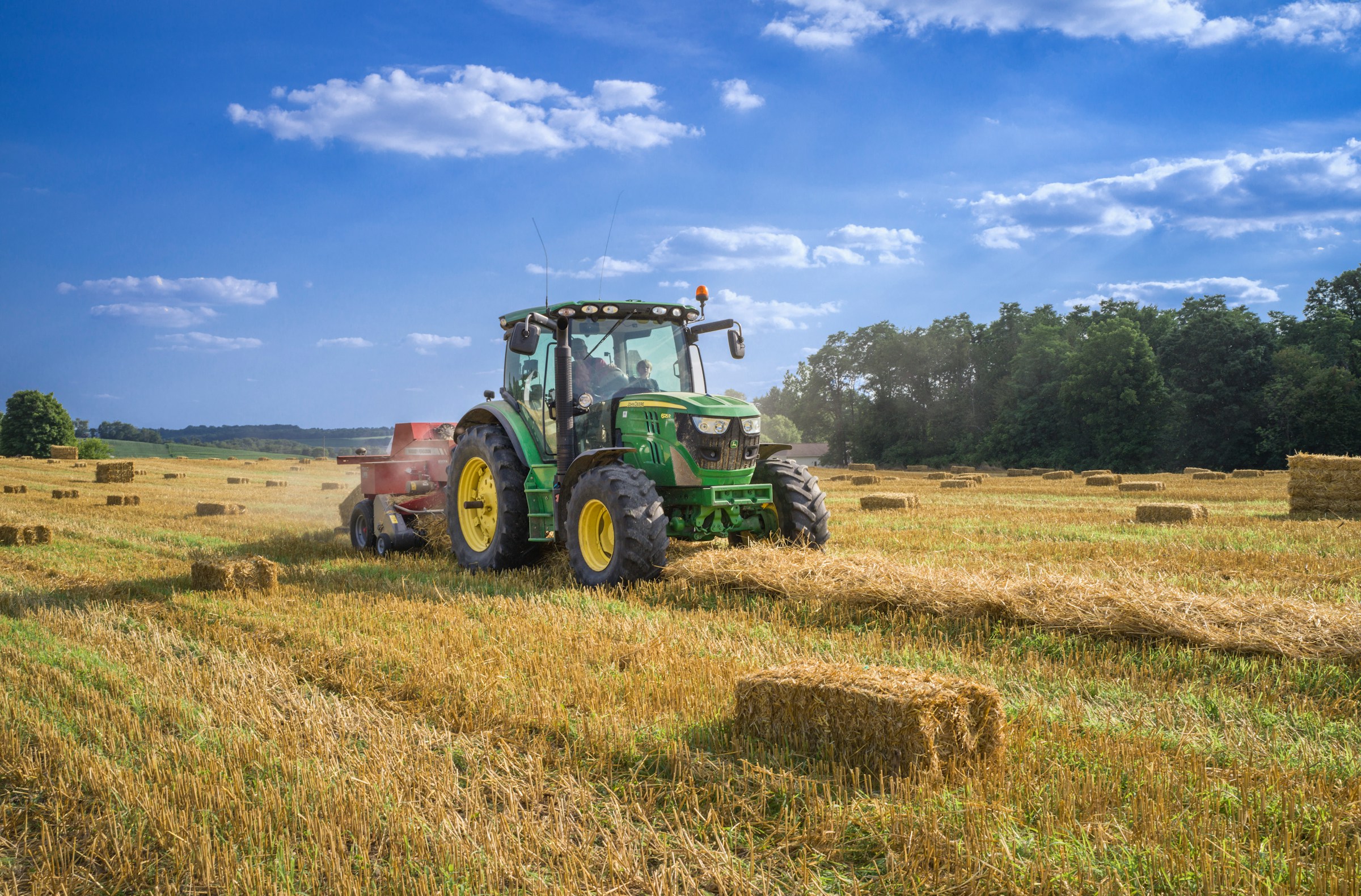A green tractor harvesting hay for the agriculture industry.