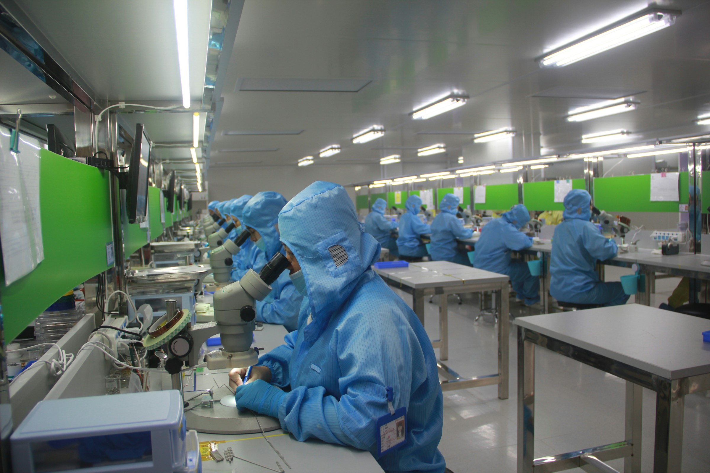 A pharmaceutical laboratory with multiple technicians in blue protective gear.